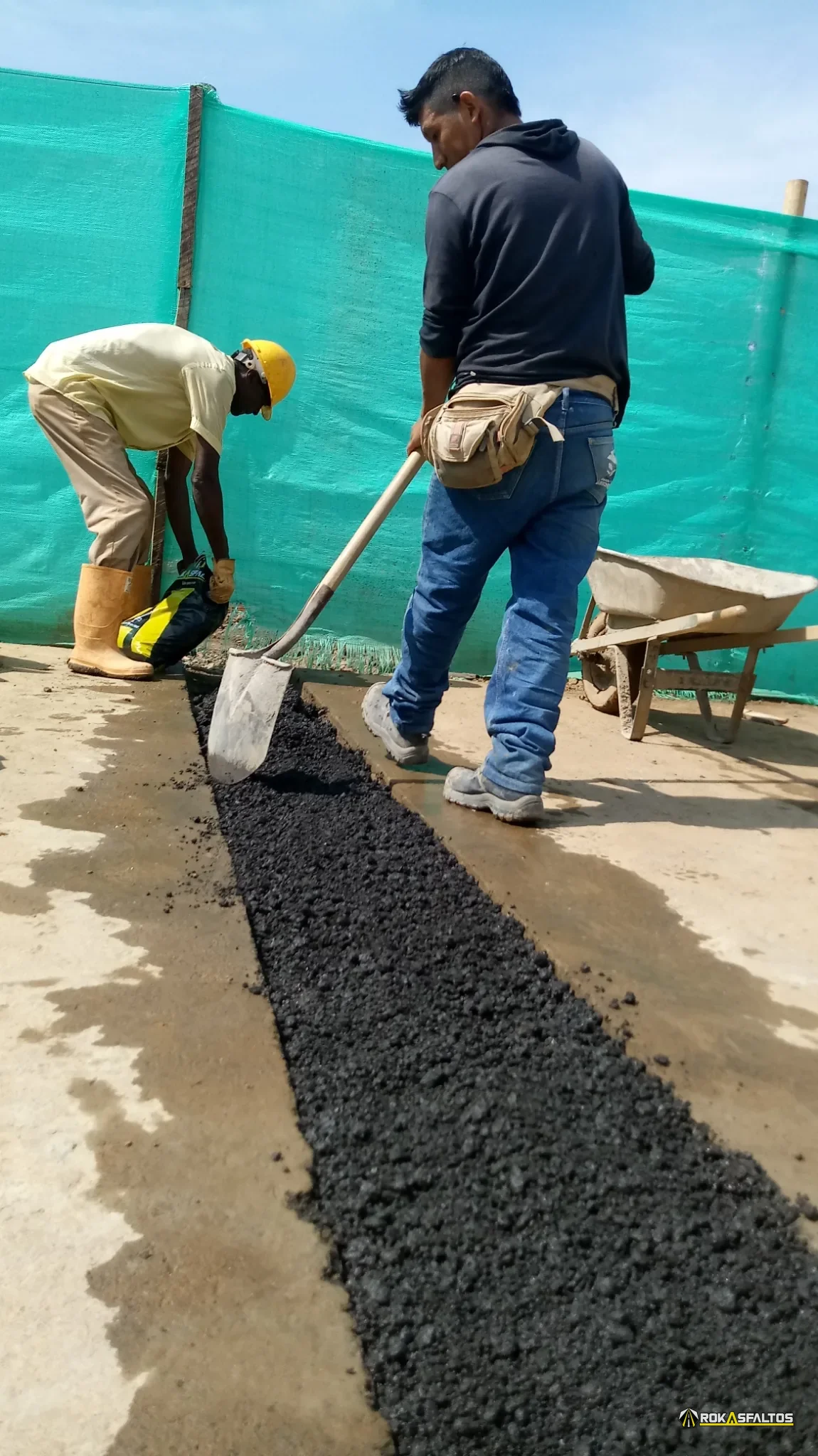 Operario distribuyendo y nivelando mezcla en una zanja